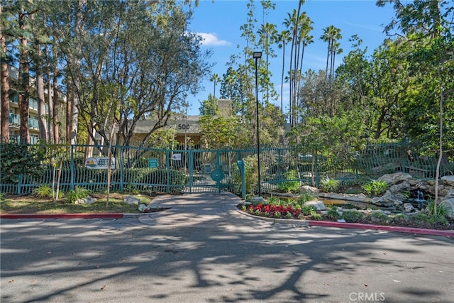 view of street featuring curbs, a gated entry, and street lighting