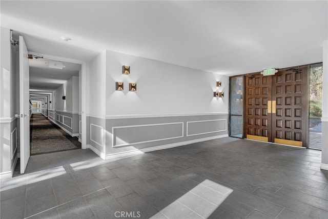 interior space featuring floor to ceiling windows, a decorative wall, and a wainscoted wall