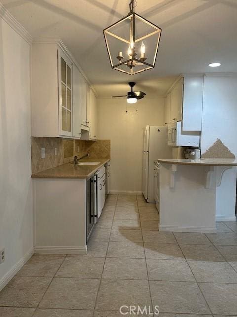 kitchen with white appliances, a peninsula, decorative backsplash, white cabinets, and glass insert cabinets