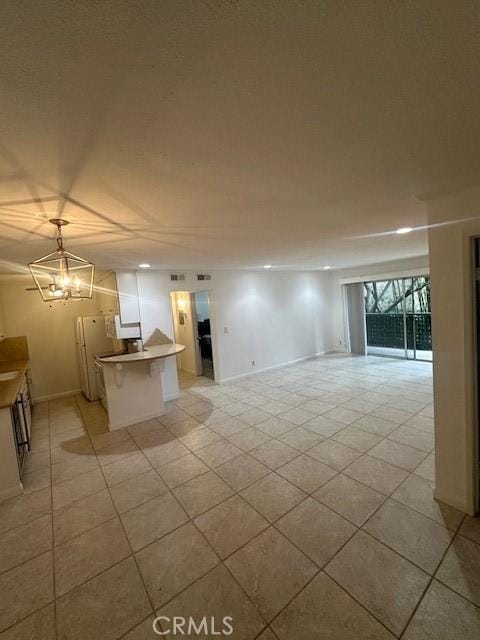 unfurnished living room featuring light tile patterned flooring, baseboards, and an inviting chandelier