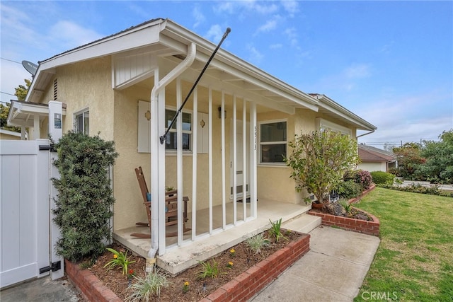 view of exterior entry featuring a yard and stucco siding