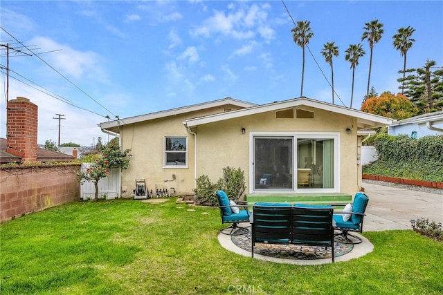 rear view of property featuring a patio, a lawn, and stucco siding