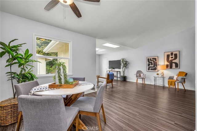 dining space with a skylight, ceiling fan, baseboards, and wood finished floors