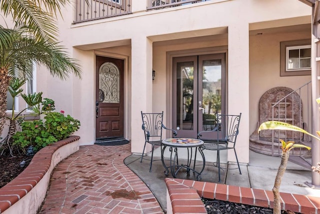 doorway to property with french doors, a balcony, and stucco siding