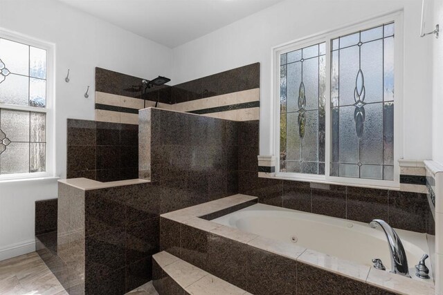 bathroom with plenty of natural light, a whirlpool tub, and walk in shower