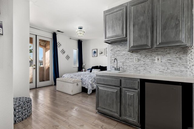 kitchen with visible vents, light wood-style flooring, french doors, open floor plan, and backsplash