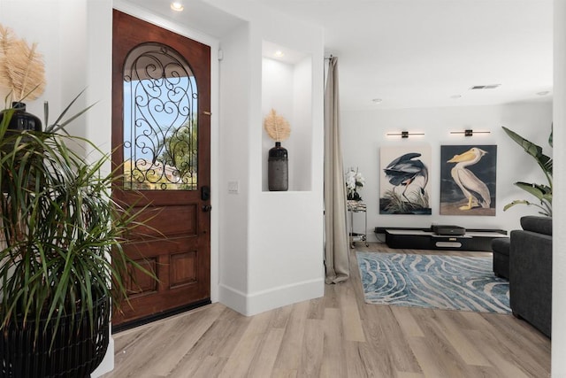 foyer entrance with visible vents, baseboards, and wood finished floors