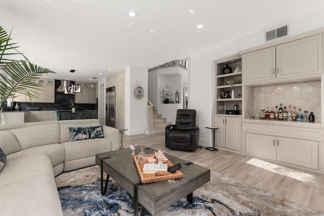 living room with visible vents, recessed lighting, stairs, a dry bar, and light wood-type flooring