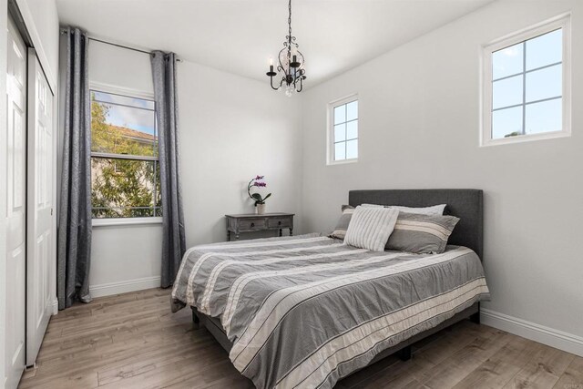 bedroom featuring a notable chandelier, baseboards, and wood finished floors