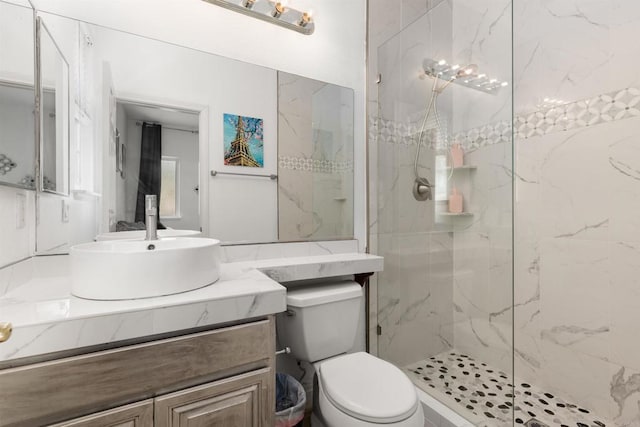 full bathroom with a marble finish shower, toilet, and vanity