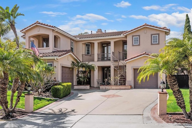 mediterranean / spanish home featuring stairway, an attached garage, stucco siding, concrete driveway, and a tiled roof