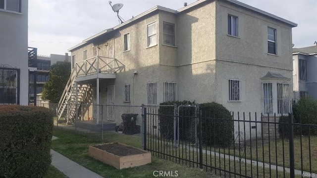 view of property exterior with fence, a vegetable garden, and stucco siding