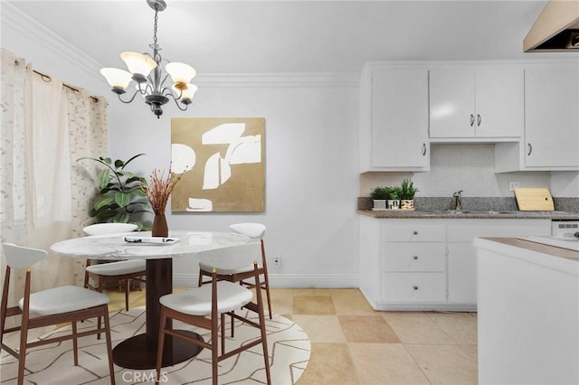 kitchen with backsplash, crown molding, an inviting chandelier, and a sink