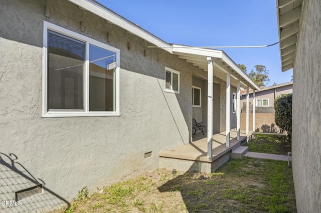 view of side of property with crawl space and stucco siding