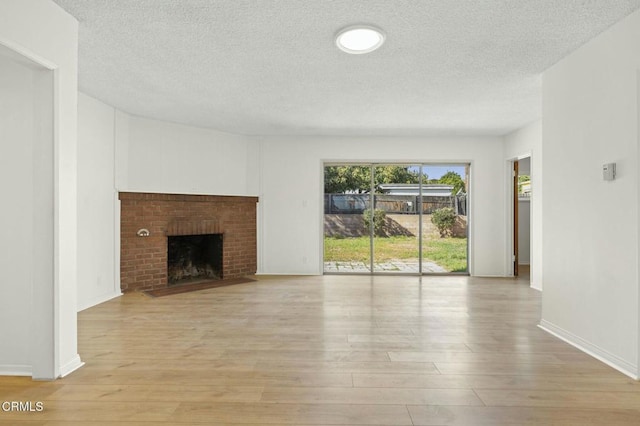 unfurnished living room with light wood-style floors, a fireplace, baseboards, and a textured ceiling