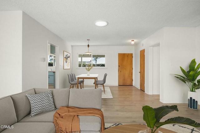 living room with light wood-type flooring, a textured ceiling, and baseboards