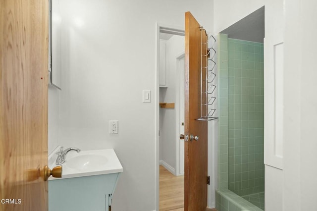 full bath featuring tiled shower and vanity