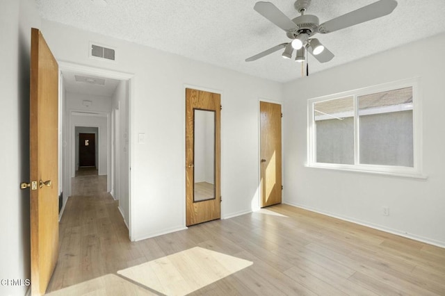 unfurnished bedroom with light wood finished floors, visible vents, a ceiling fan, a textured ceiling, and baseboards