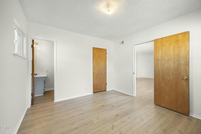 unfurnished bedroom with baseboards, a textured ceiling, and light wood finished floors