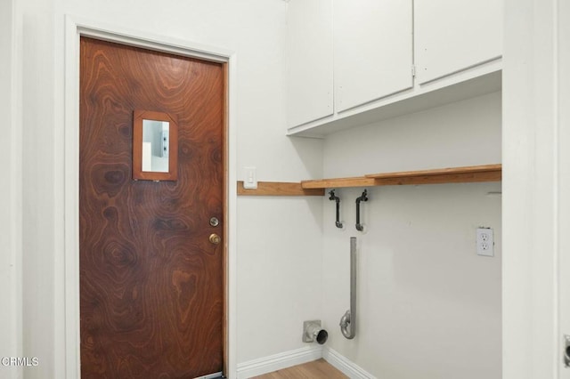 laundry area with cabinet space, baseboards, and wood finished floors