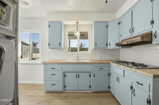 kitchen featuring stainless steel gas cooktop, a sink, under cabinet range hood, and backsplash