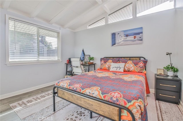 bedroom featuring lofted ceiling with beams, wood finished floors, and baseboards