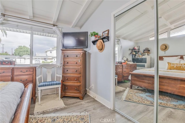 bedroom with a closet, vaulted ceiling with beams, baseboards, and wood finished floors