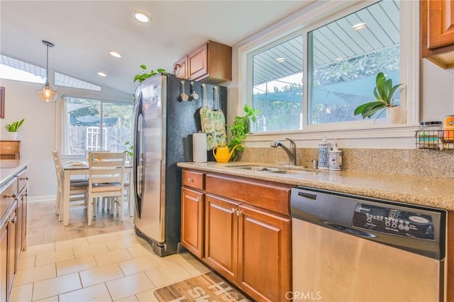 kitchen featuring appliances with stainless steel finishes, brown cabinetry, a sink, and a wealth of natural light