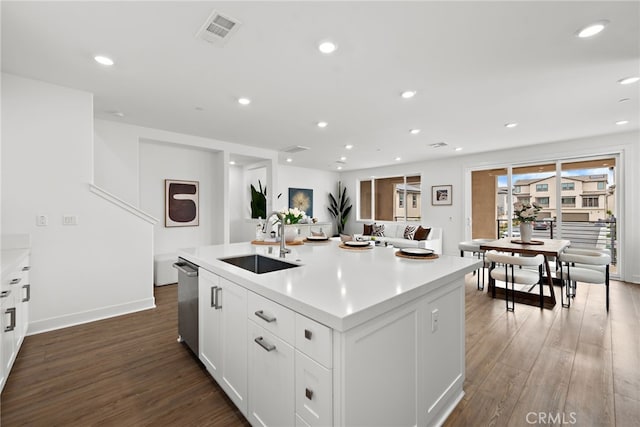 kitchen with visible vents, dark wood-type flooring, an island with sink, a sink, and stainless steel dishwasher