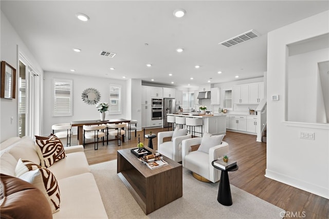 living area with light wood-style flooring, recessed lighting, visible vents, and a wealth of natural light