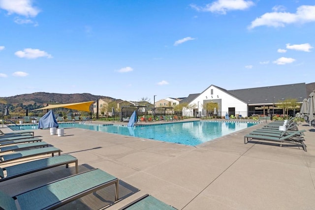 pool featuring a patio, fence, and a mountain view