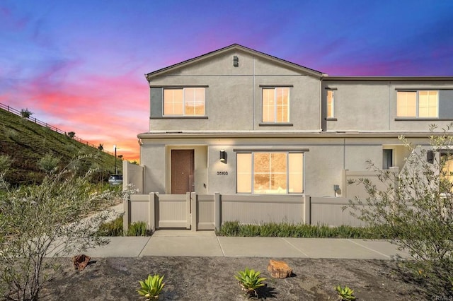 traditional-style house with a fenced front yard, a gate, and stucco siding