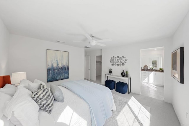 bedroom featuring a ceiling fan, a walk in closet, visible vents, and light colored carpet