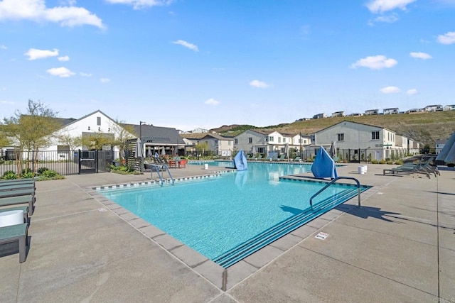 pool with a patio area, a residential view, and fence