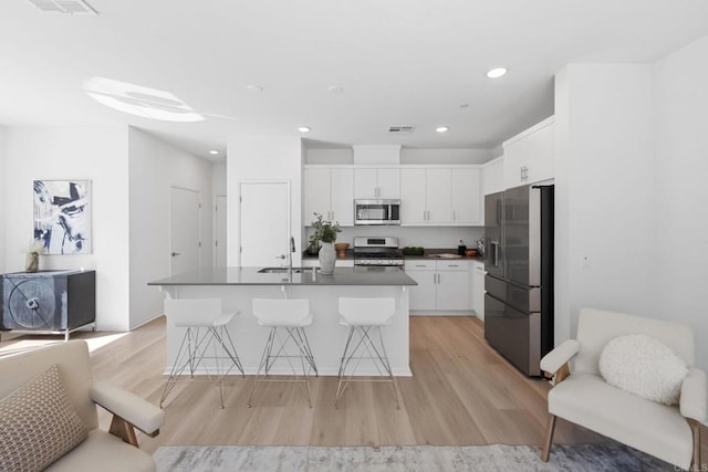 kitchen featuring a breakfast bar area, a sink, visible vents, white cabinets, and appliances with stainless steel finishes