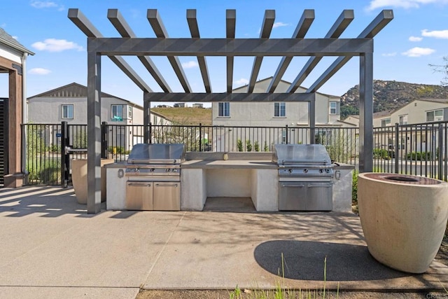 view of patio with exterior kitchen, a grill, fence, and a pergola