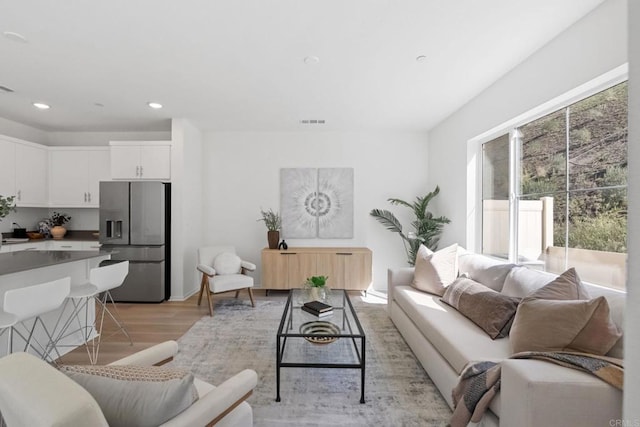 living area with light wood-style flooring, visible vents, and recessed lighting