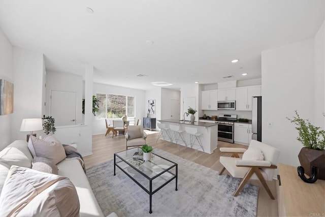 living area with recessed lighting, visible vents, and light wood-style floors