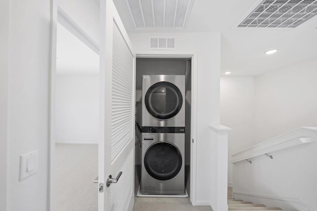 laundry room featuring stacked washer and clothes dryer, visible vents, and laundry area