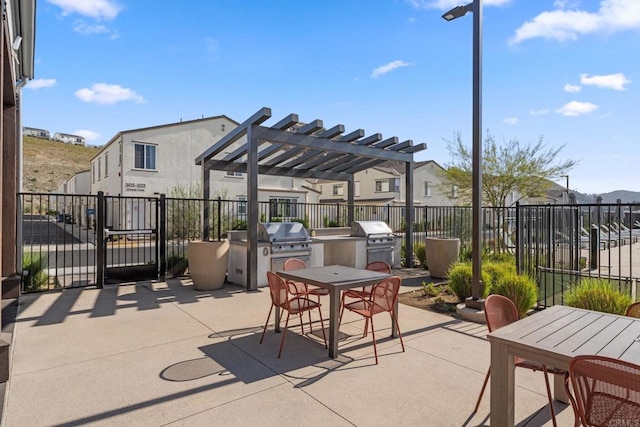 view of patio featuring an outdoor kitchen, fence, grilling area, a pergola, and outdoor dining space