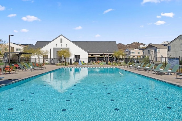 community pool featuring a patio area, fence, and a residential view