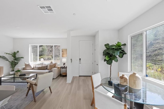 living room with light wood-type flooring, a healthy amount of sunlight, and visible vents