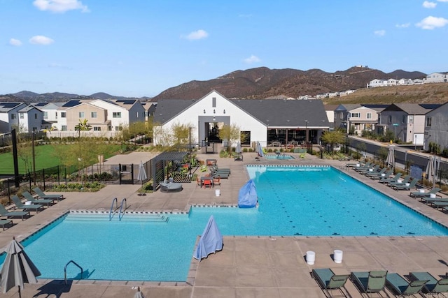 pool with a residential view, fence, a patio, and a mountain view