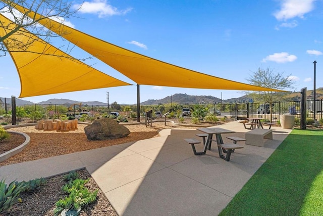 view of home's community with a mountain view, a patio, and fence