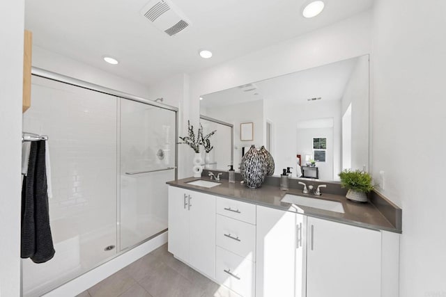 bathroom with visible vents, a sink, a shower stall, and double vanity