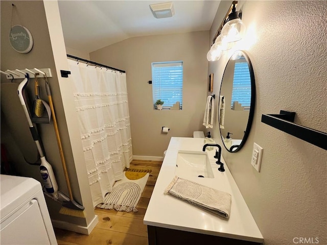 full bathroom with a shower with shower curtain, wood finished floors, vanity, vaulted ceiling, and washer / dryer