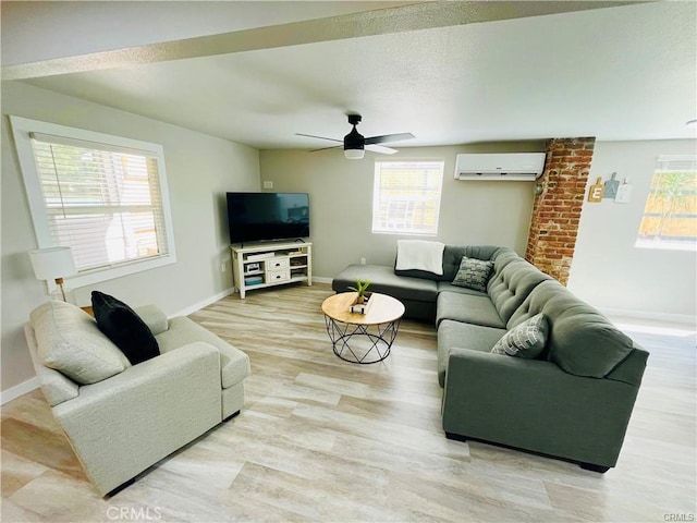 living area featuring baseboards, light wood-style floors, a wall mounted air conditioner, and a healthy amount of sunlight