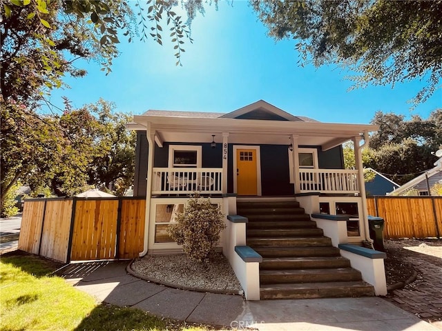 view of front of property with covered porch, fence, and stairs