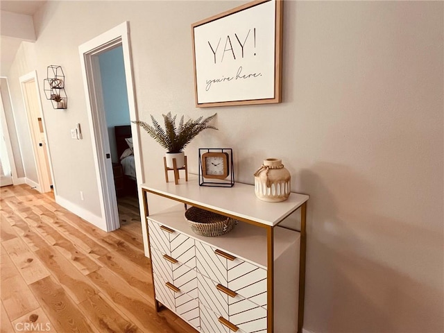 hallway featuring light wood finished floors and baseboards