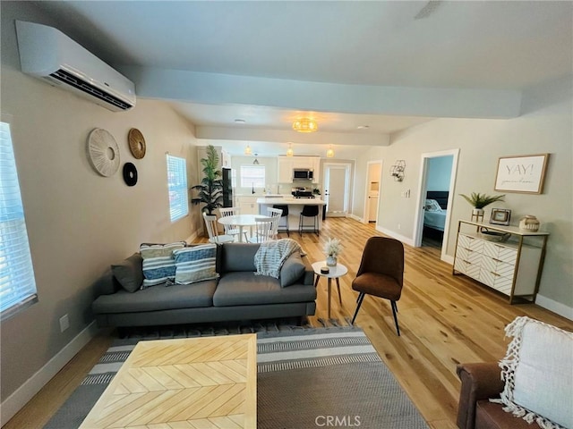 living room featuring light wood-style flooring, baseboards, and a wall mounted air conditioner